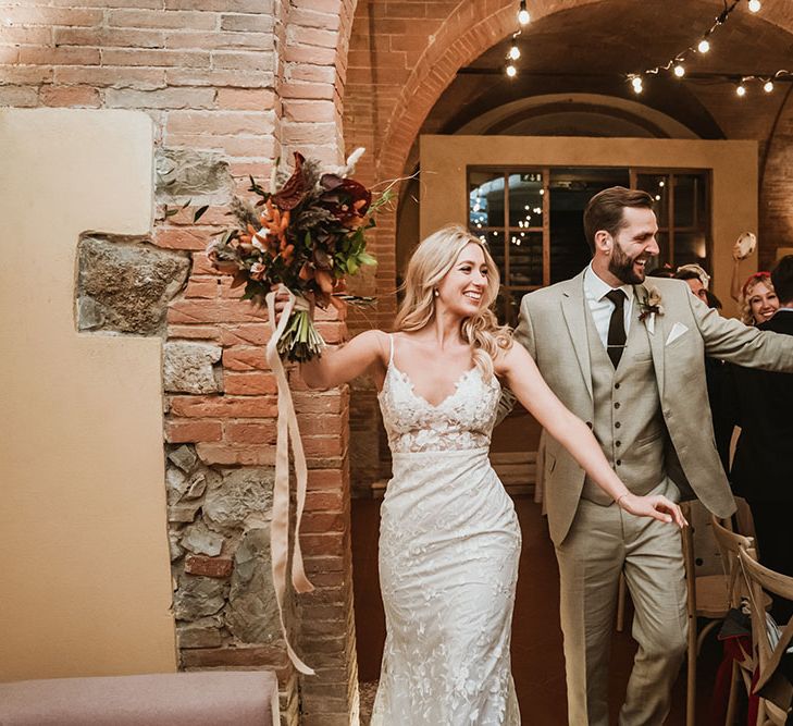 Bride & groom walk through wedding reception venue the Villa Catignano in Tuscany 