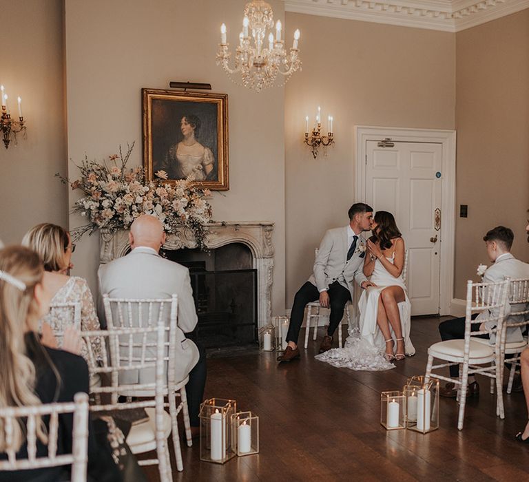 Wedding guests sit for the intimate wedding ceremony with the bride and groom sharing a kiss 