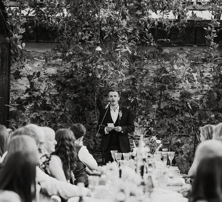 Best man gives a wedding speech as the guests listen 