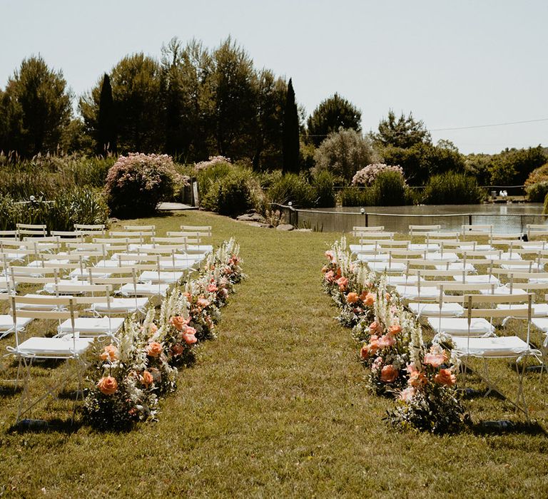 Outdoor wedding ceremony in Mas Loisonville with white chairs and peony arrangements lining the aisle 