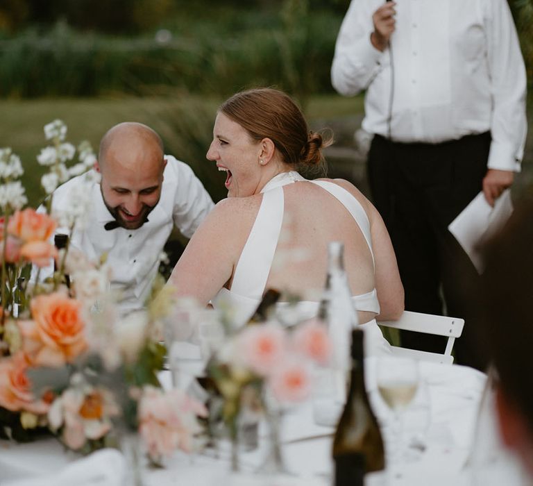 Bride & groom laugh during outdoor wedding reception speeches for destination wedding 