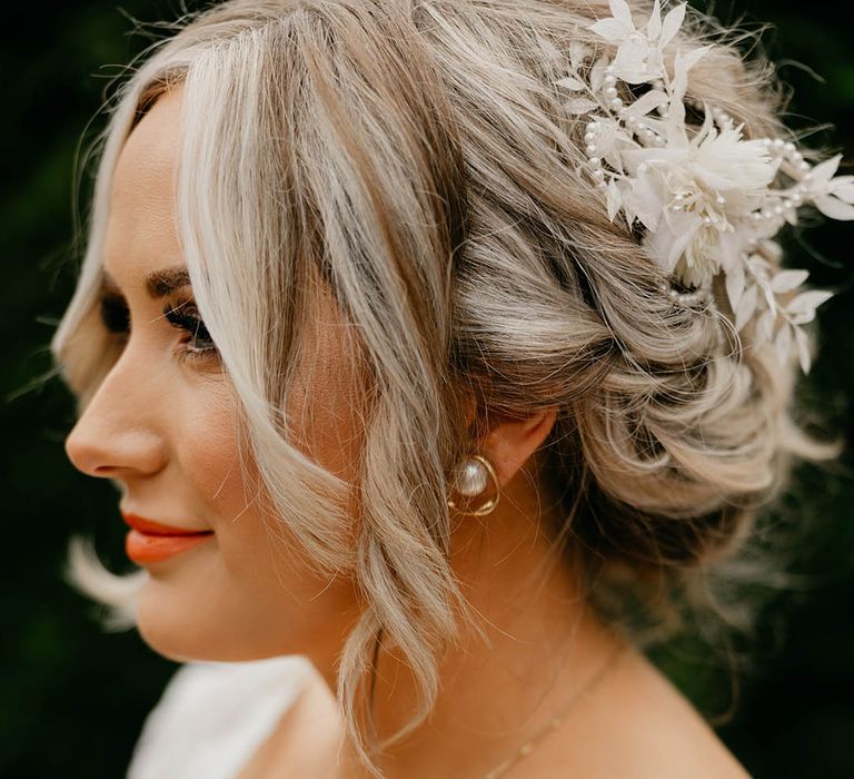 Bride with pearl earrings with blonde updo with pearl and white flower hair accessory