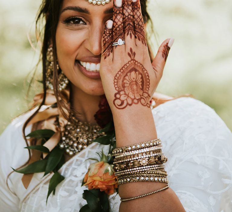 Bride wearing traditional Indian jewellery and headpiece with pearls and a henna design on her hand