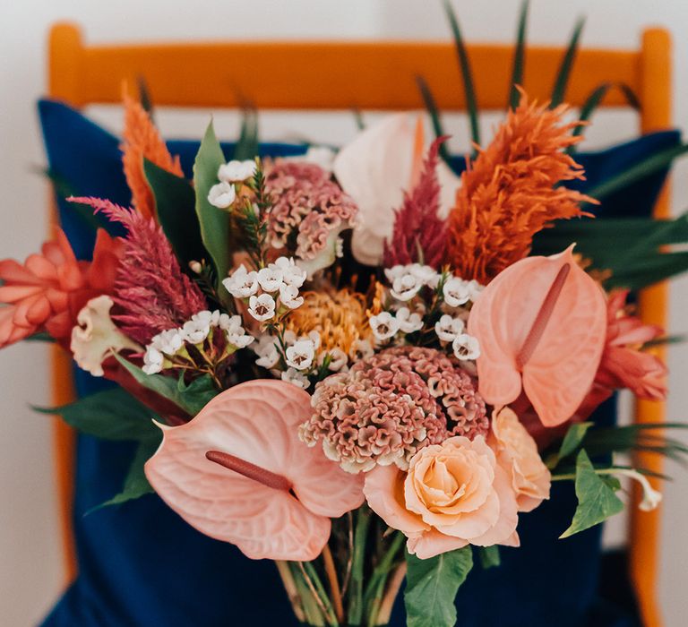 Pink and orange tropical wedding bouquet with anthuriums and palm leaves