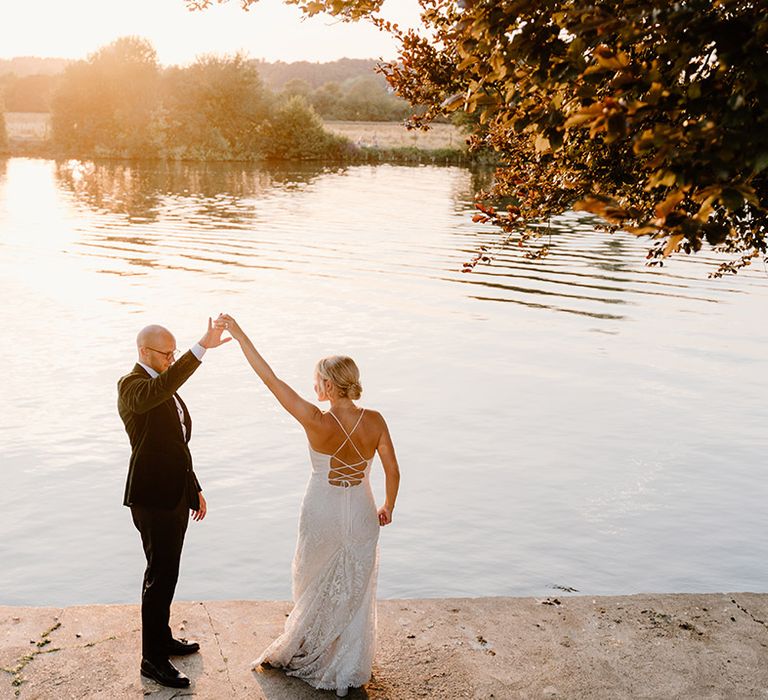 Bride & groom dance beside the River Thames on their wedding day during golden hour