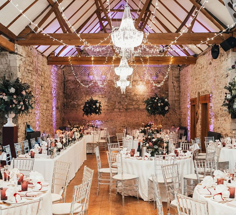 Rustic Notley Abbey wedding venue with fairy lights and tables covered in white table cloths and burgundy colour palette 