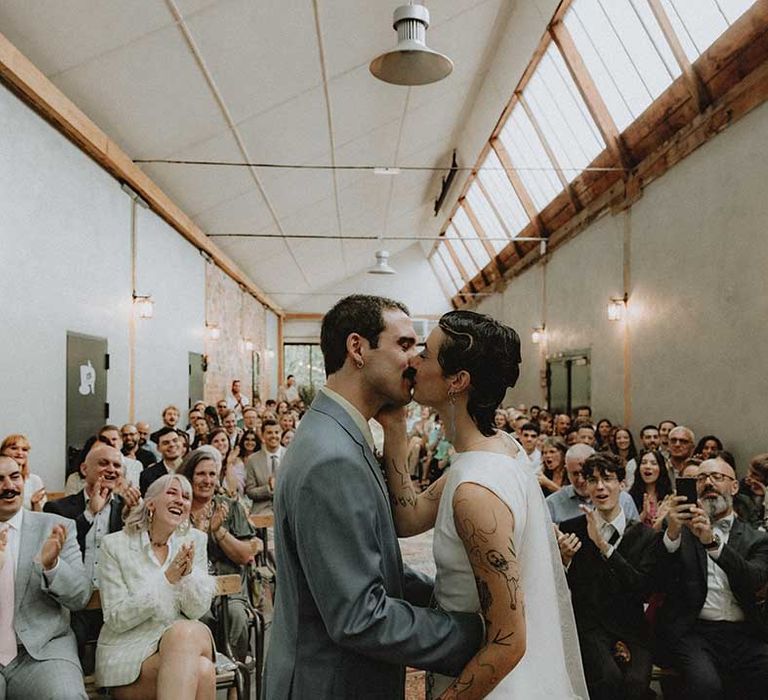 Lisa & Gabriel kiss after non-denominational wedding ceremony with industrial vibe 