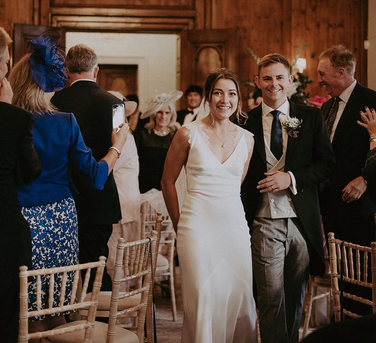 Bride & groom in Morning suit walk through Hedsor House during wedding reception