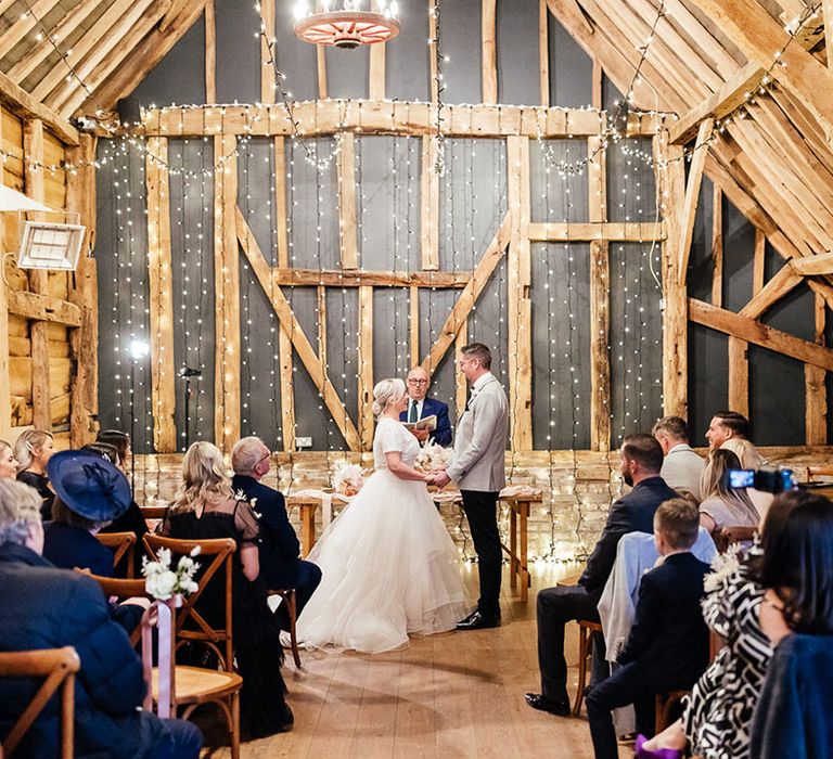 Fairy light Silchester Farm barn wedding ceremony room with the bride and groom standing at the altar 