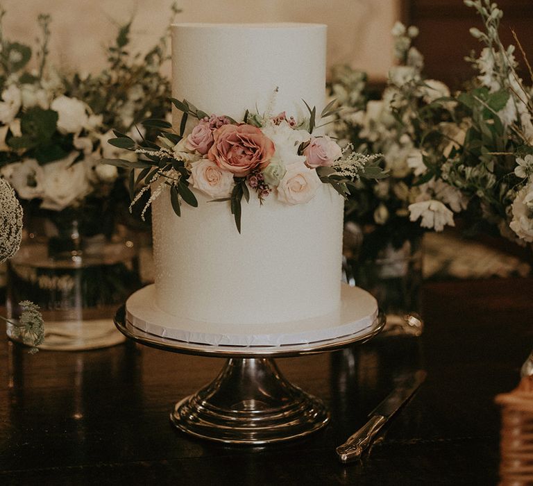 Two tier white iced wedding cake with pink and white rose decorations 