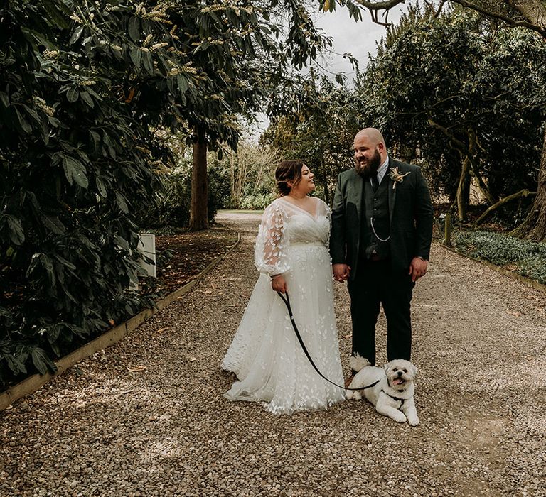 Groom in green tweed wedding suit with the bride and their pet dog 