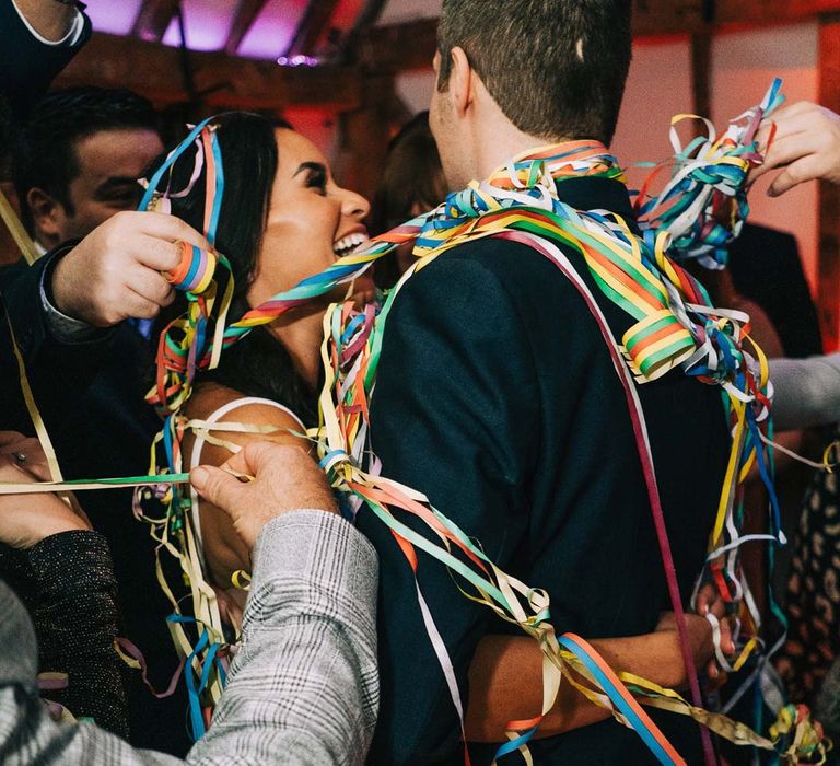 Bride and groom wrapped up in rainbow streamers during wedding first dance at South Farm wedding