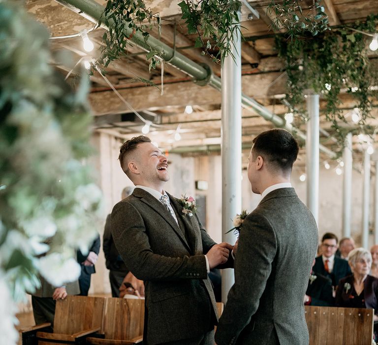 The groom and best man in grey suits laugh together on the wedding day as they wait for the bride's arrival 