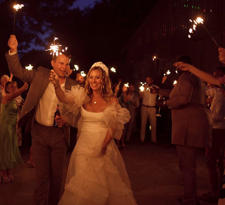 The bride and groom walk out of the wedding reception for a traditional sparkler send off 