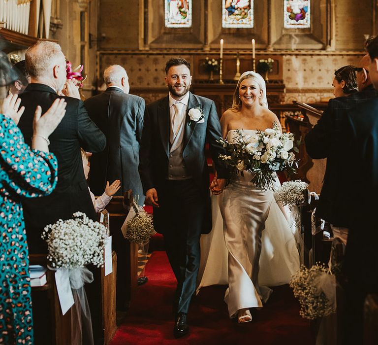 The bride and groom walk back down the aisle as a married couple 