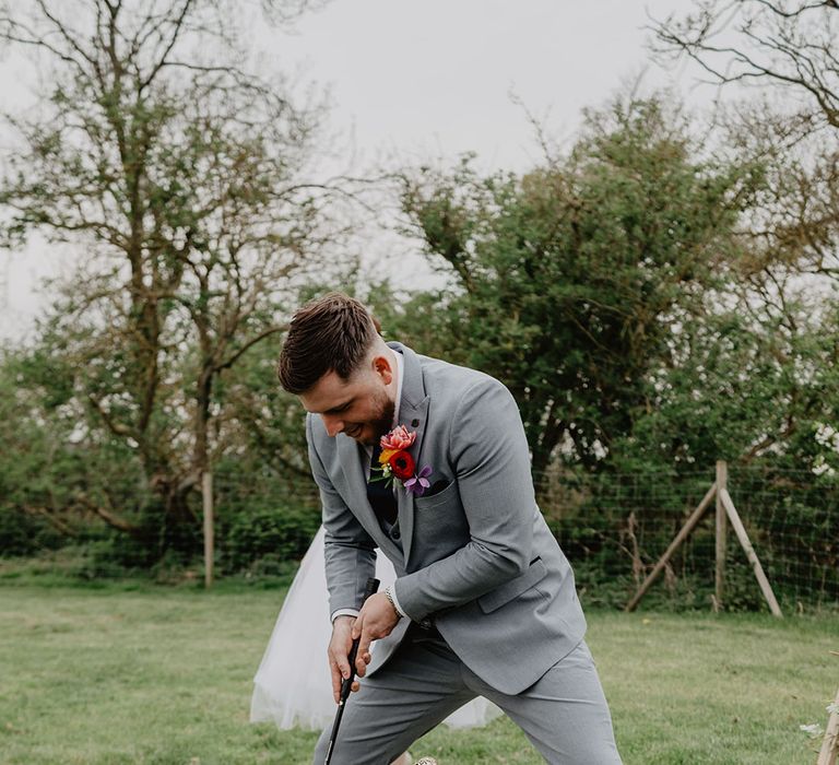 The groom plays a round of mini golf as wedding entertainment at the boho festival wedding 