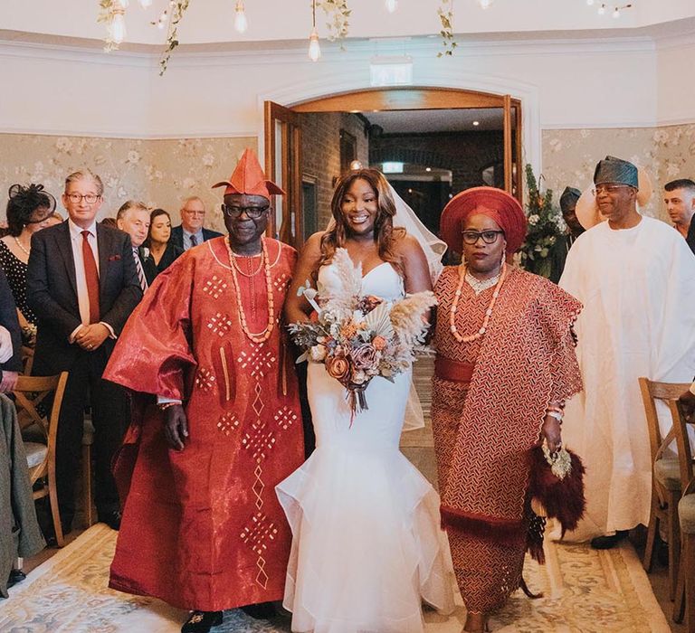 Father and mother of the bride enter the wedding ceremony with the bride for the multicultural wedding ceremony 