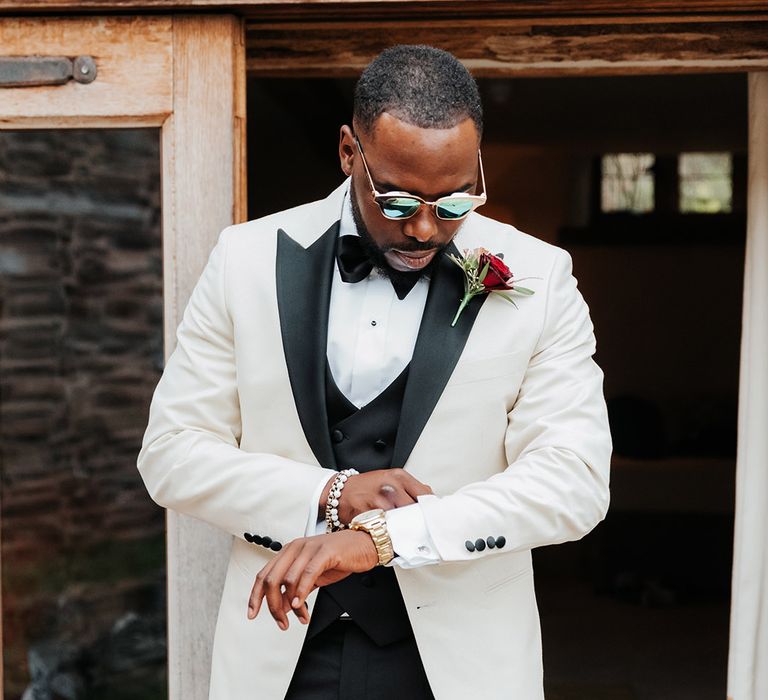 Groom in classic white tuxedo and black sunglasses for wedding day 