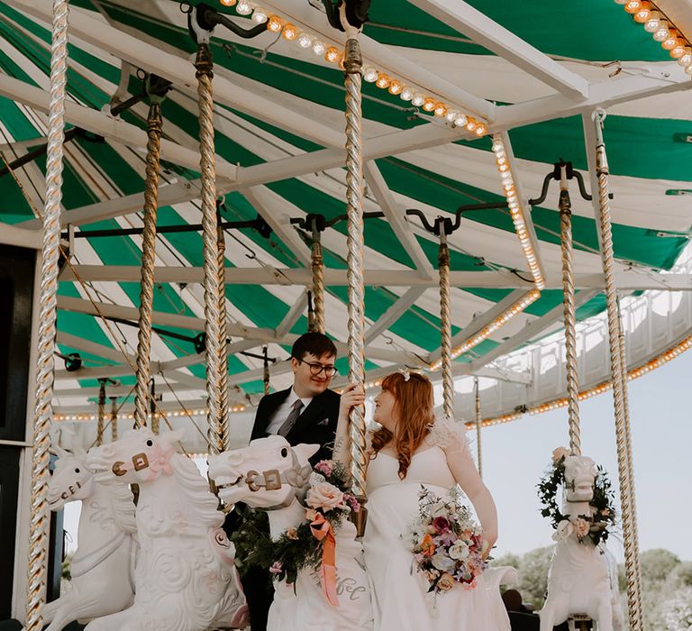 A carousel at fairground wedding with pastel wedding flowers 