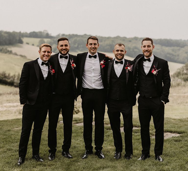 Groom and groomsmen in black tuxedos at wedding 