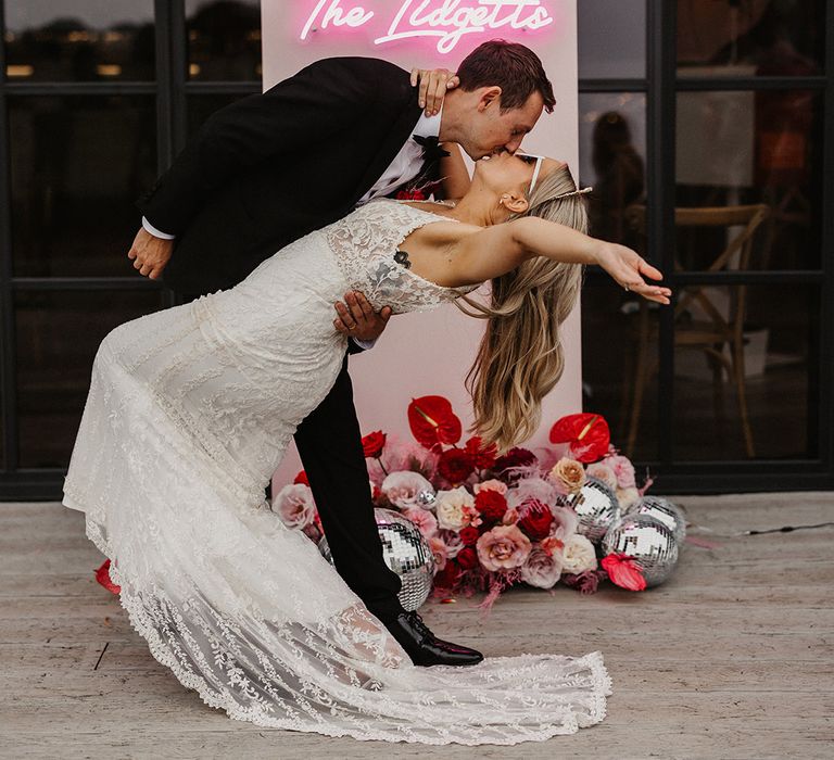 Pink customised neon wedding sign with the bride and groom kissing 