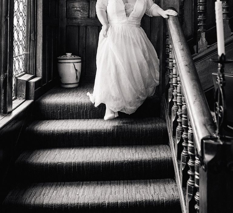 Bride in plunging neckline wedding dress with quarter length sleeves walking down the stairs 