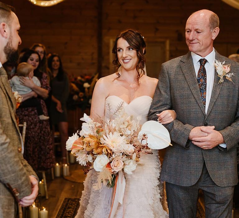 The bride is walked down the aisle by the father of the bride and meets the groom at the end of the aisle 