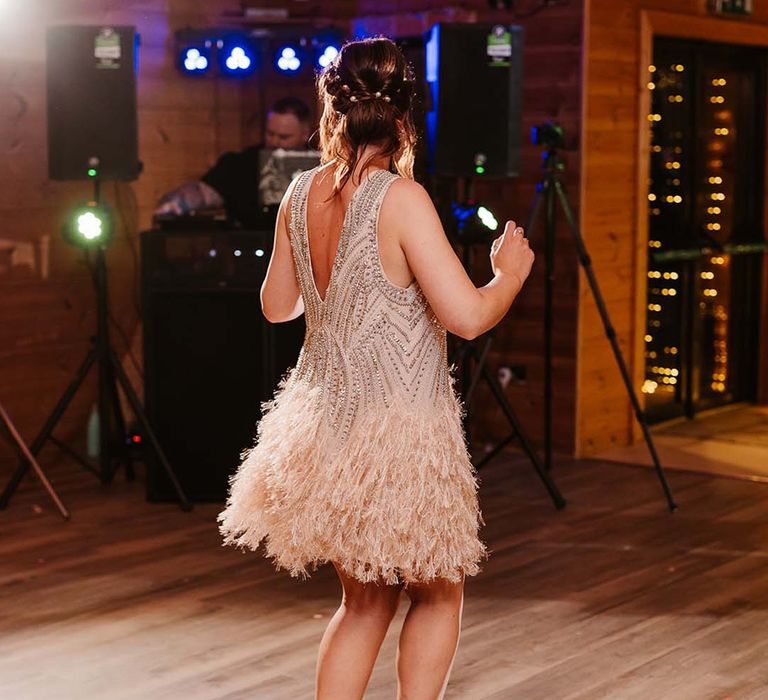 Bride wearing short feather bejewelled wedding reception dress for the evening 