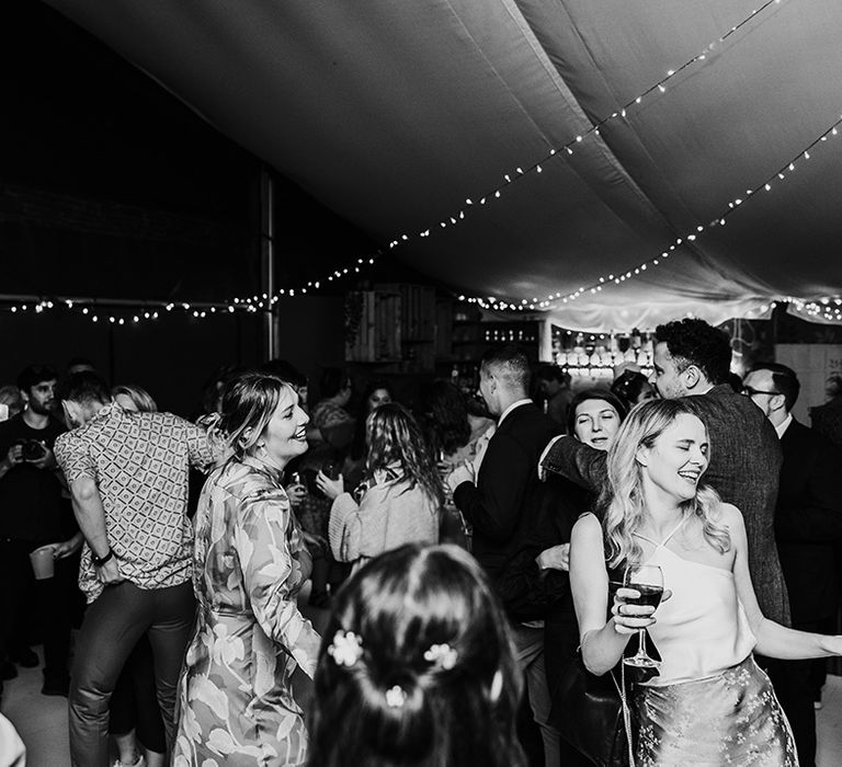 Wedding guests dance at the wedding reception decorated with fairy lights 