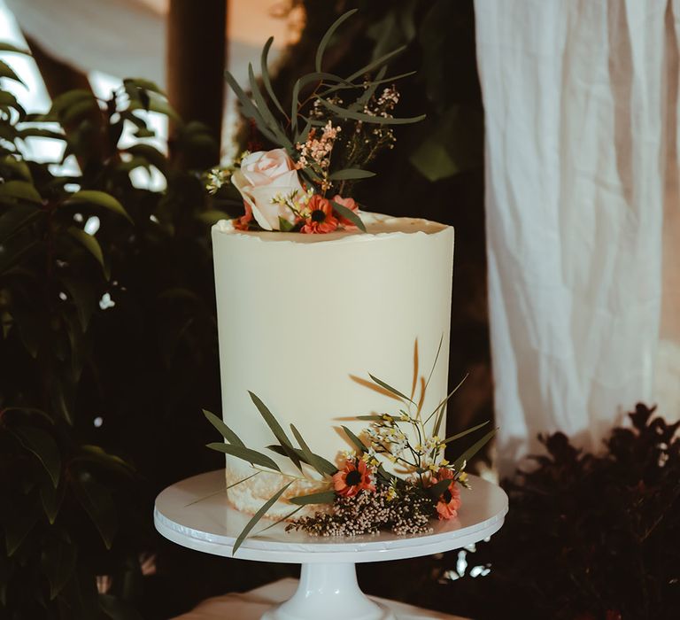 Buttercream frosted wedding cake with foliage and flower decorations 