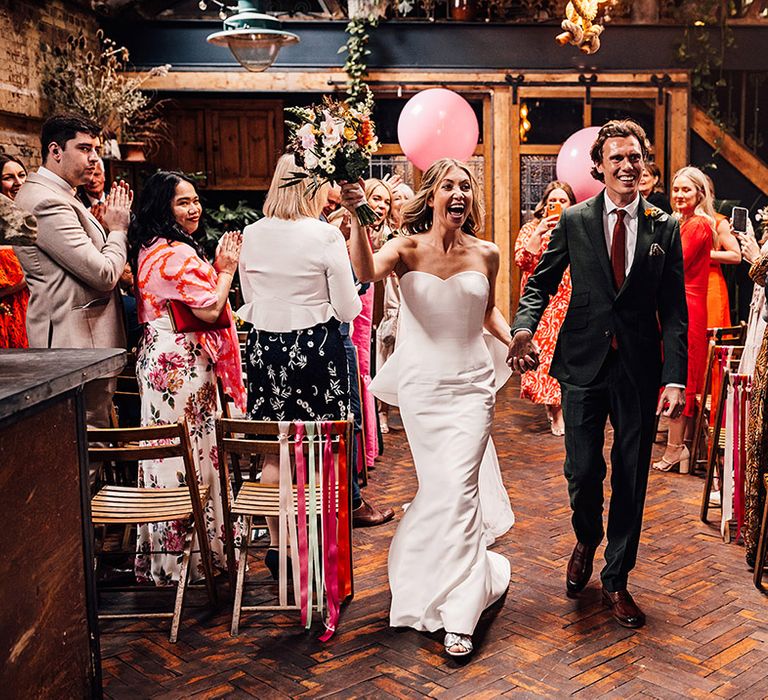 Couple walking back down the aisle at Clapton Country Club with large pink balloons 