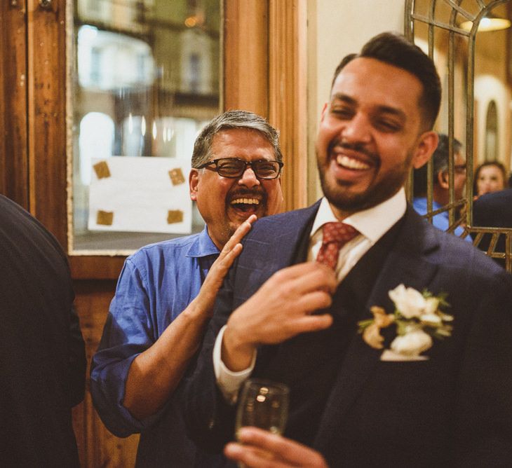 Groom laughing at wedding reception with red tie