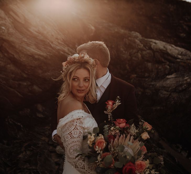 Bride and groom pose in front of the rocks on Anglesey Island at golden hour 