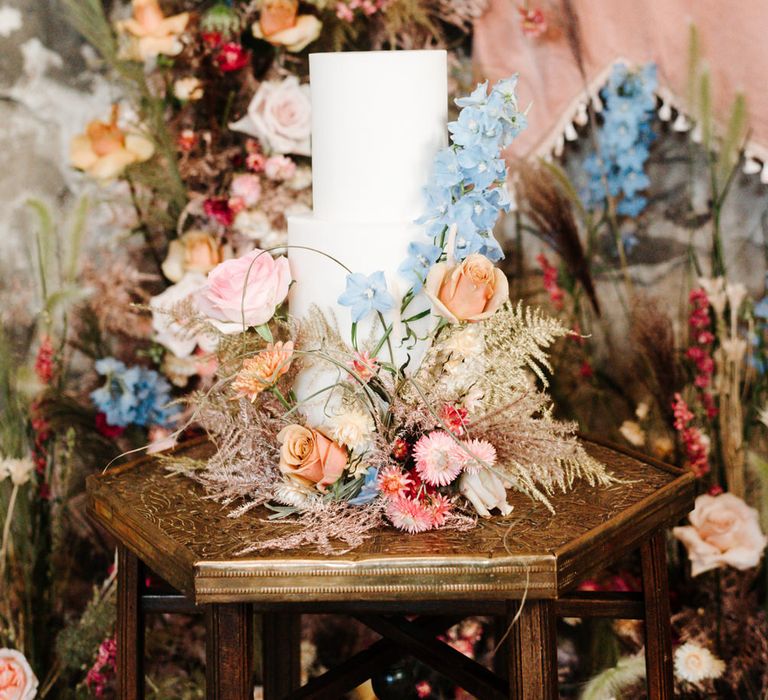 White wedding cake decorated with colourful wedding flowers 