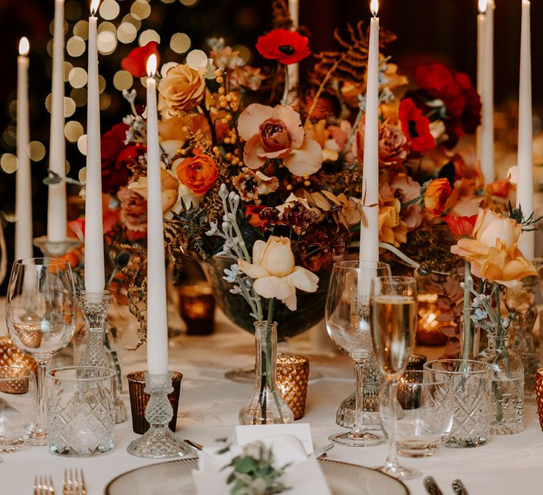 Winter wedding tablescape with large centrepiece of warm neutral tones and tapered candles.