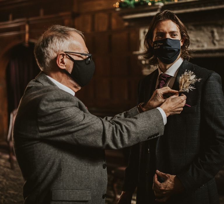 Father of the groom putting his son dried flower buttonhole on 