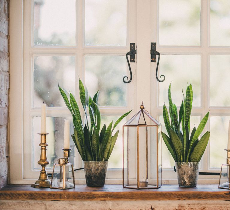 Green plants and golden candle holders on windowsill at Iscoyd Park wedding reception