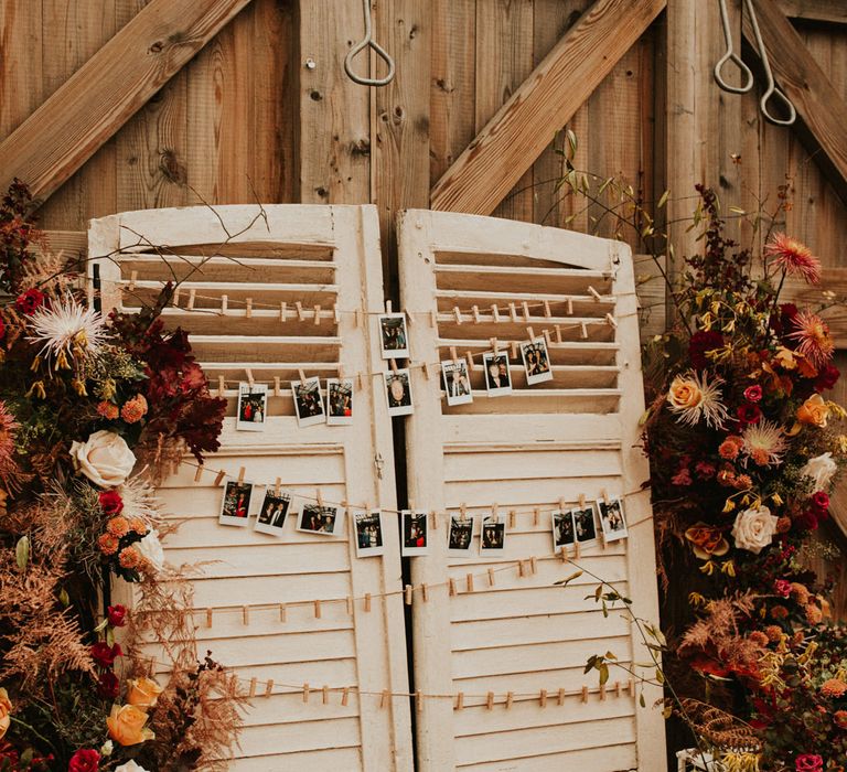 Autumn themed wedding decor shutter display with orange, red and yellow wedding flowers 