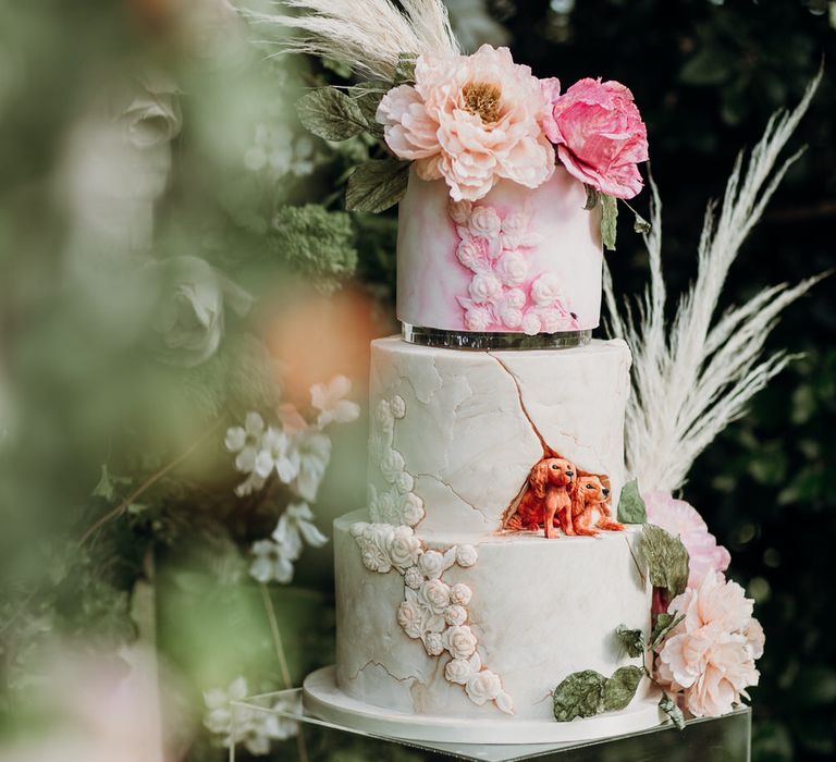 Three tier marble effect wedding cake with blush pink watercolour detailing, two dogs and rose, ranunculus and pampas grass decor by Cherry Tree Cakerie