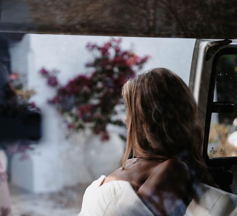 A bride sits in a VW Camper van looking out of the door. The shot is from the back of her head. Photography by Stephanie Shenton.