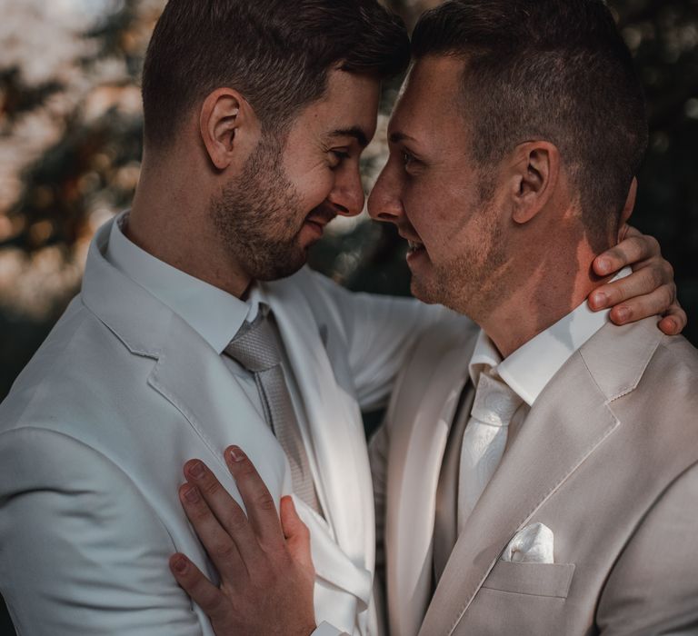 Grooms in light grey wedding suit embrace