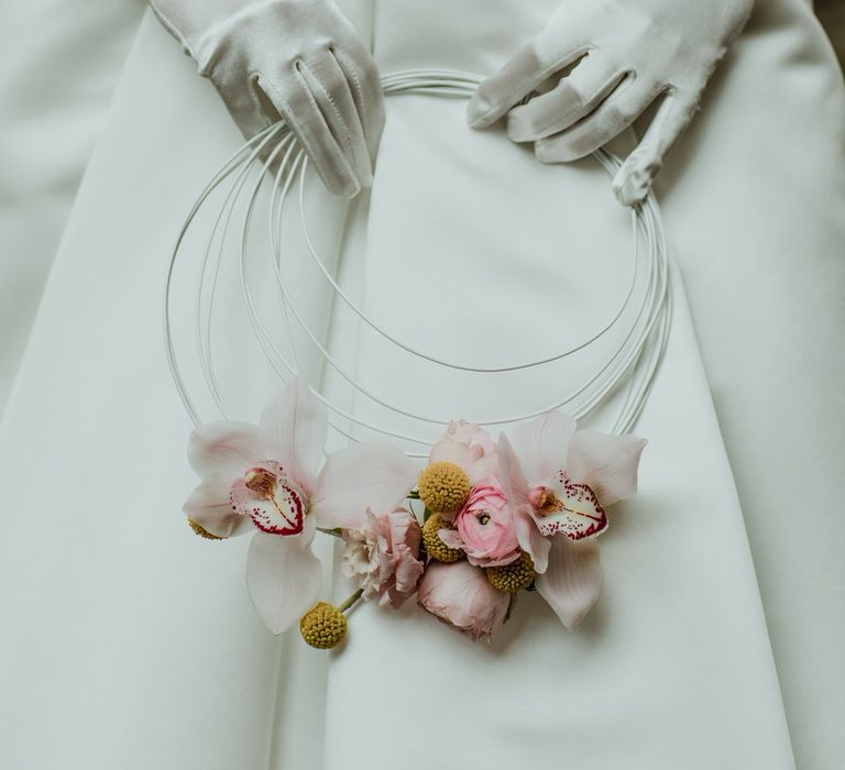 White bridal gloves and vintage style wedding dress, holding a white minimal bridal hoop with orchids