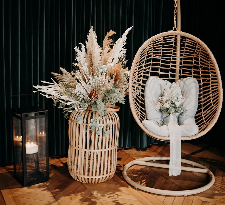 Wicker chair with pillow and wicker vase holding pampas grass bouquet 