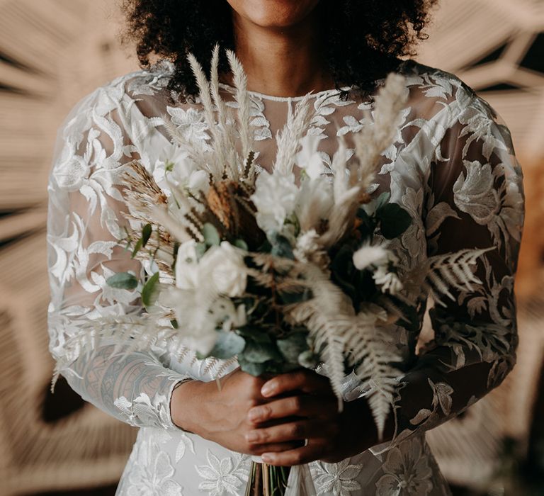 Black bride wears gold head piece and holds floral bouquet whilst laughing