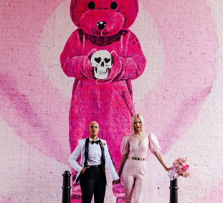 Alternative bride and bride standing in front of a pink teddy graffiti wall in Shoreditch 