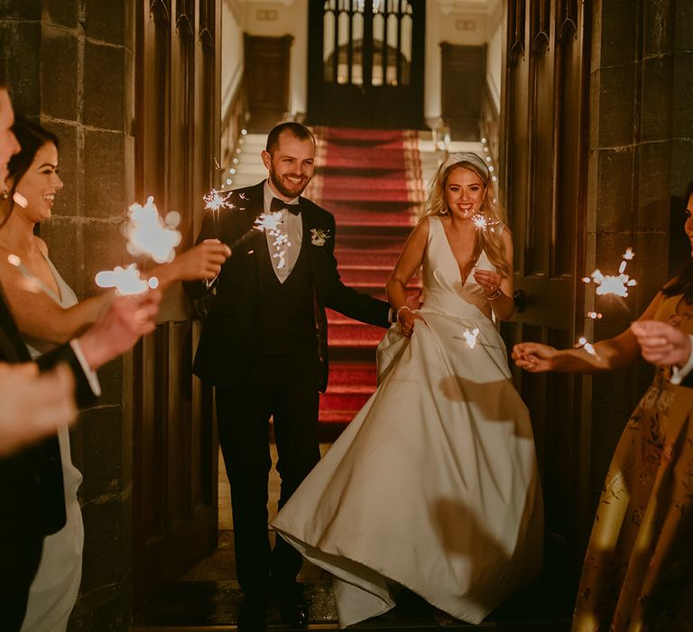 Bride & groom walk outside with sparklers on their wedding day 