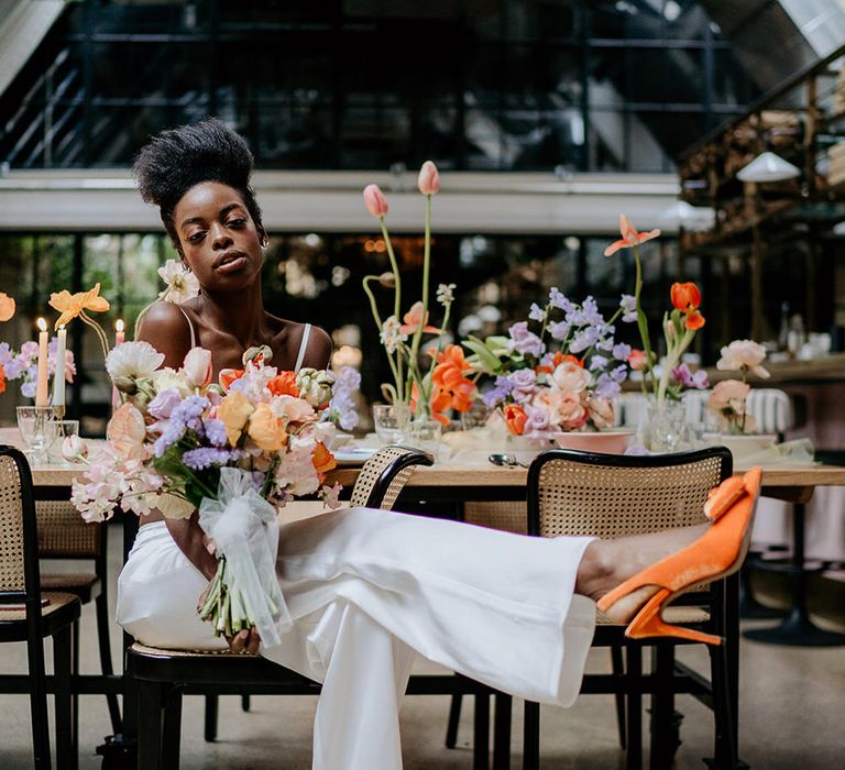 Bride in a white bridal trouser separates and orange bow sling back wedding shoes 