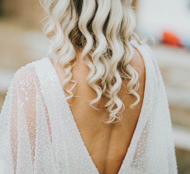 Bride in a sparkly wedding dress with low V back detail and long wavy wedding hair