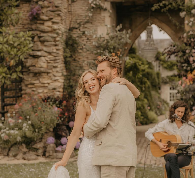 Groom in beige suit dancing with his bride in a Made With Love dress at Euridge Manor 