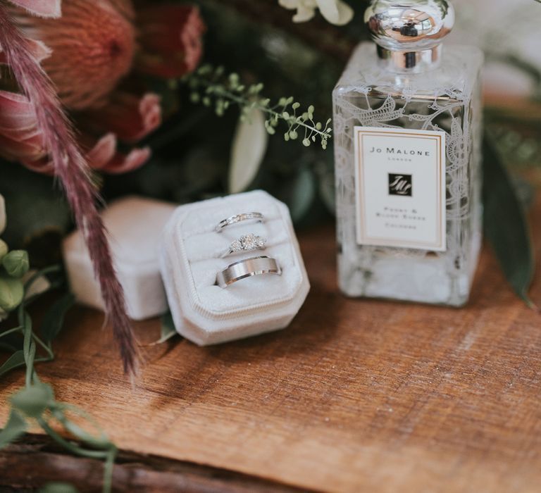 Jo Malone perfume bottle, three silver rings in white box and bridal bouquet with white florals and pink protea at Tythe Barn wedding with barn wedding flowers